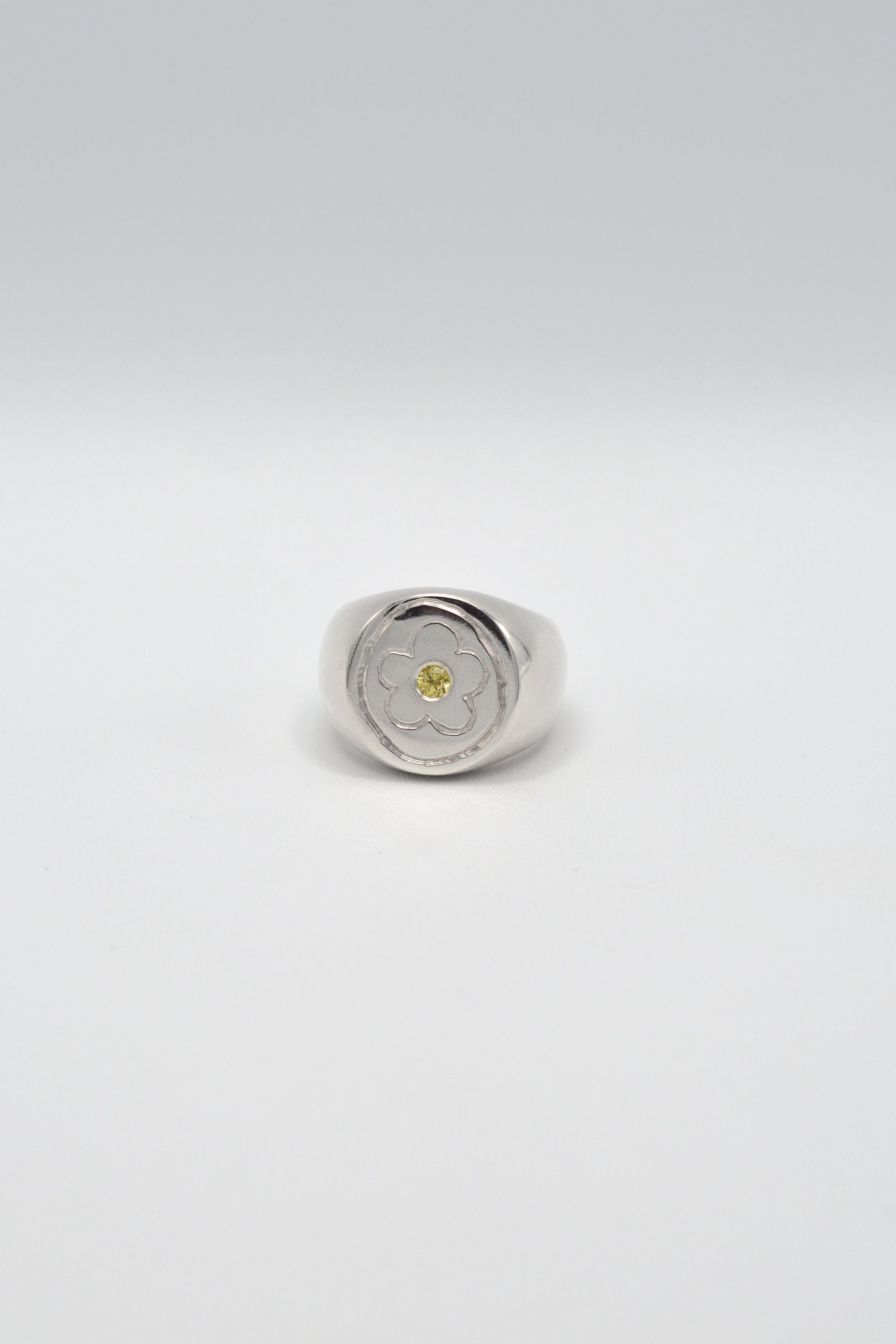 Silver ring with a yellow gemstone on a light gray background