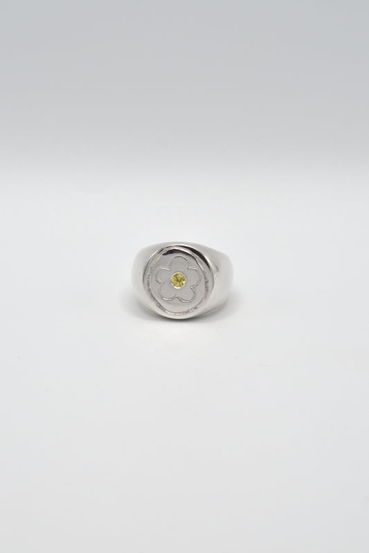 Silver ring with a yellow gemstone on a light gray background