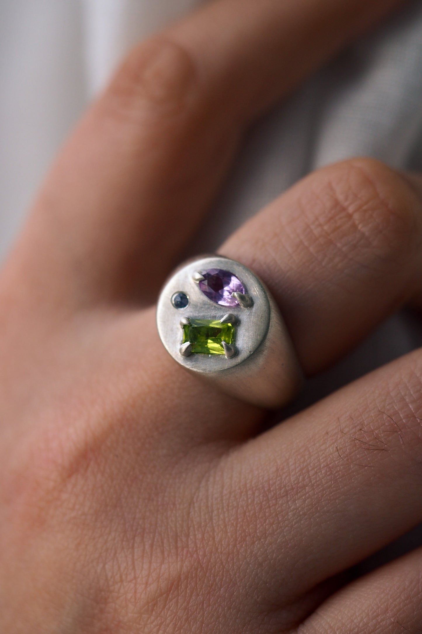 Silver ring with multicolored gemstones on a hand